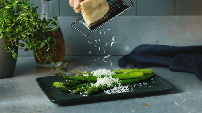 Le fromage est râpé sur un plateau d'asperges.